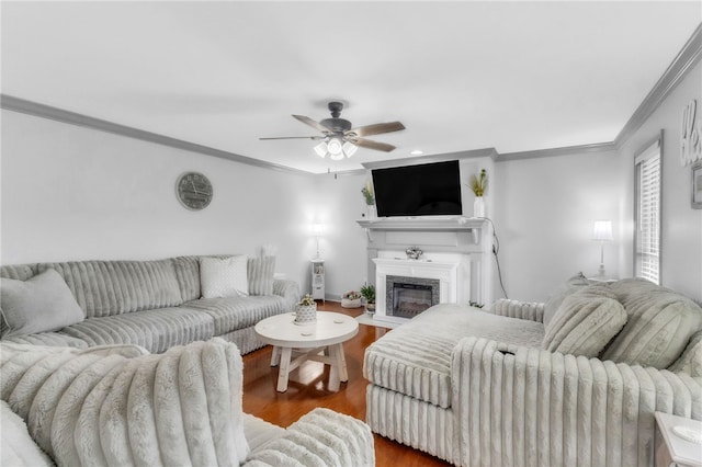 living room with a fireplace with flush hearth, ornamental molding, a ceiling fan, and wood finished floors