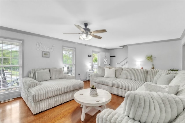 living area featuring visible vents, ornamental molding, a ceiling fan, and wood finished floors