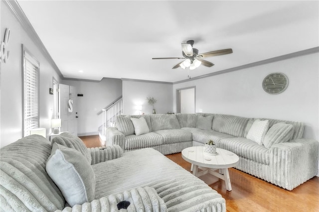 living room with light wood-type flooring, ornamental molding, stairs, and ceiling fan