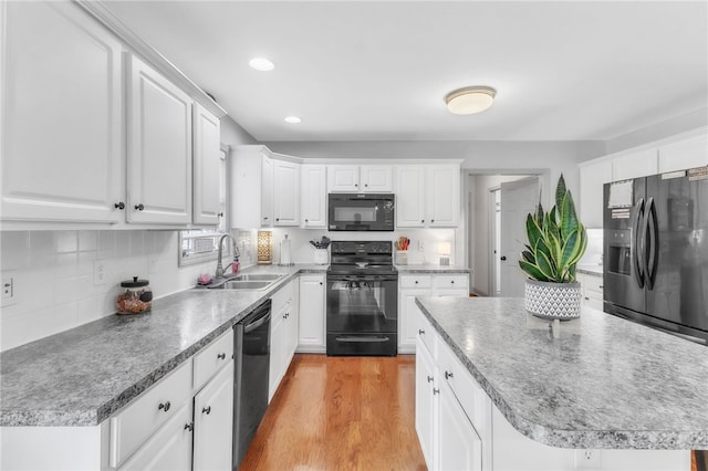 kitchen with white cabinets, a sink, a center island, tasteful backsplash, and black appliances