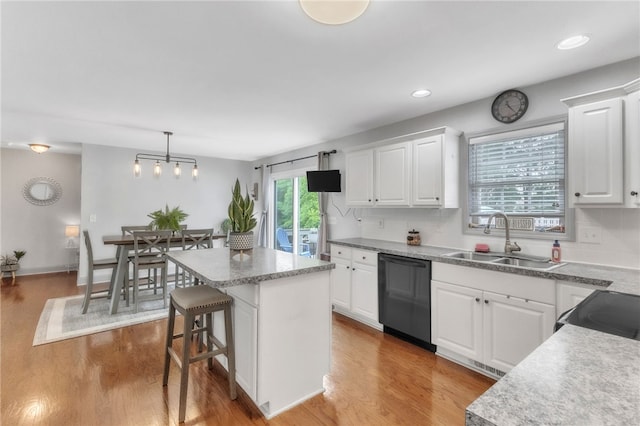 kitchen featuring a kitchen island, a sink, black appliances, and wood finished floors