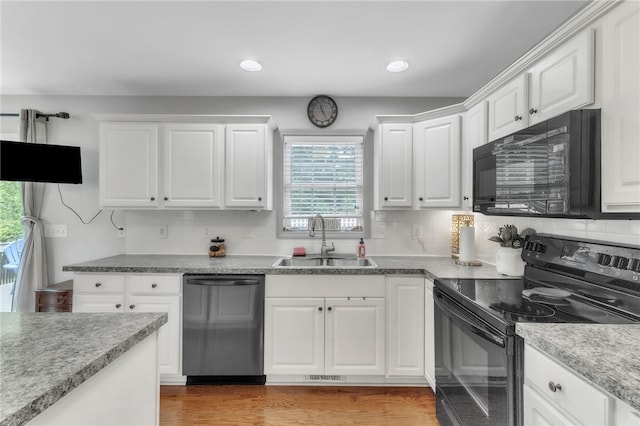 kitchen featuring plenty of natural light, a sink, white cabinetry, and black appliances