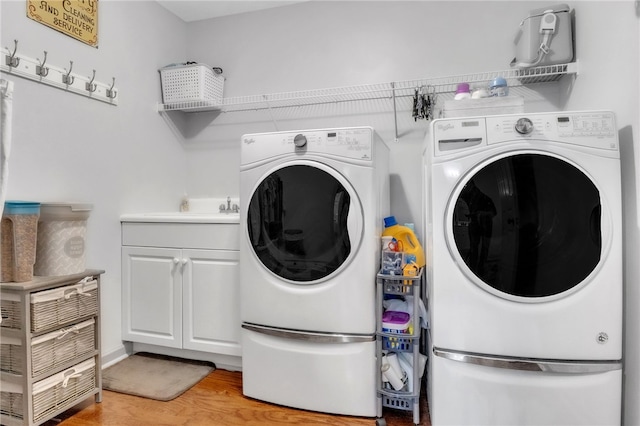laundry room featuring light wood-style floors, washer and clothes dryer, cabinet space, and a sink