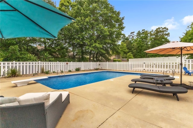 view of pool featuring a fenced in pool, a diving board, a fenced backyard, and a patio area