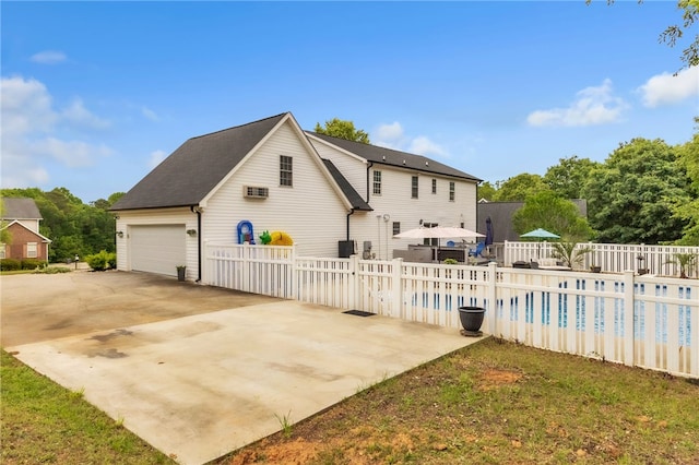 rear view of property with fence, a fenced in pool, and a garage