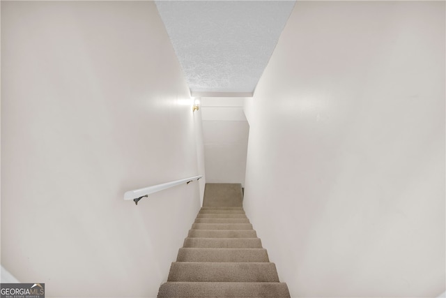 staircase with a textured ceiling