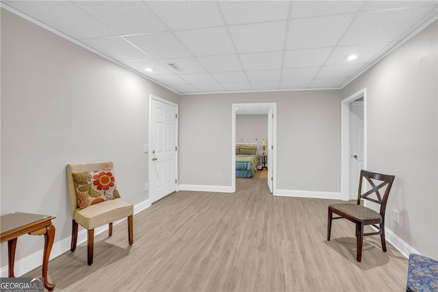 sitting room featuring baseboards, light wood-style flooring, and a drop ceiling