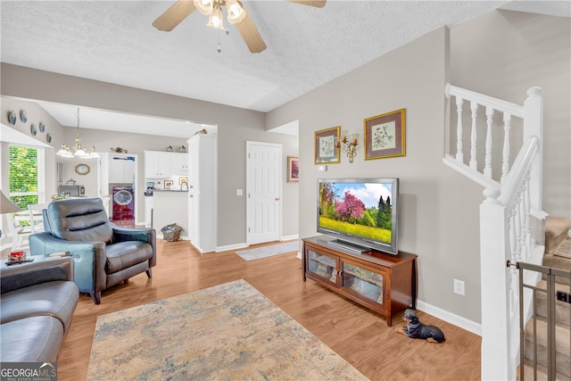 living room with baseboards, a ceiling fan, light wood-style flooring, and a textured ceiling