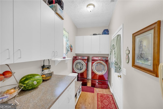 laundry area with light wood-style floors, a textured ceiling, cabinet space, and washer and dryer