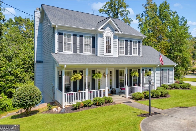 view of front of property featuring a front lawn, roof with shingles, covered porch, and a chimney
