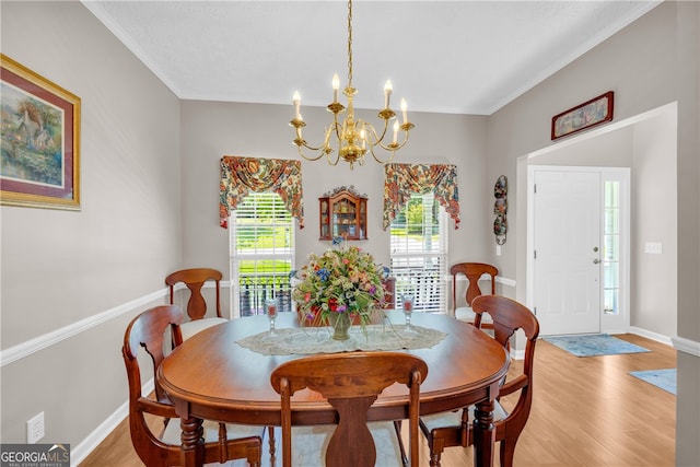 dining room with baseboards, an inviting chandelier, ornamental molding, and light wood-type flooring