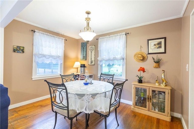 dining space featuring baseboards, ornamental molding, and wood finished floors