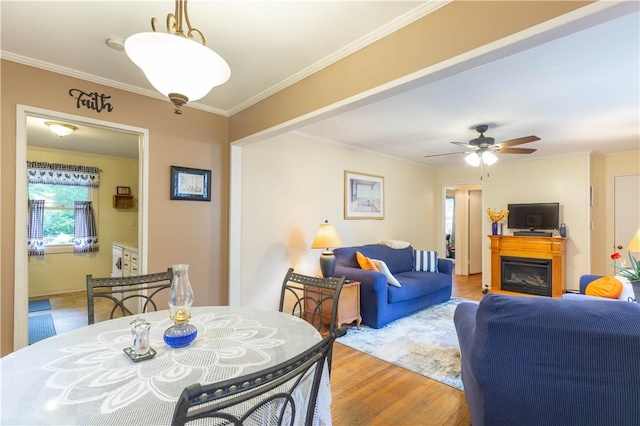 dining space with crown molding, plenty of natural light, a ceiling fan, and wood finished floors