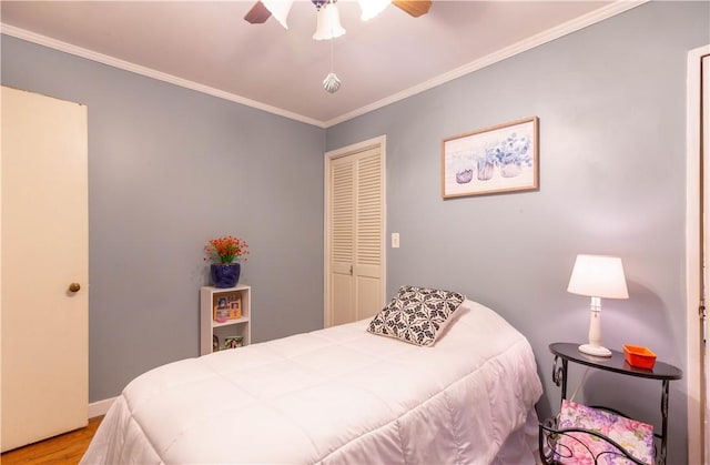 bedroom with crown molding, ceiling fan, baseboards, wood finished floors, and a closet