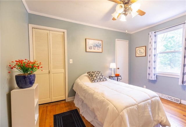 bedroom featuring visible vents, ornamental molding, wood finished floors, baseboards, and a ceiling fan