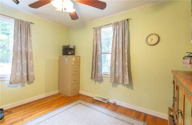 interior space featuring a ceiling fan, visible vents, ornamental molding, and wood finished floors