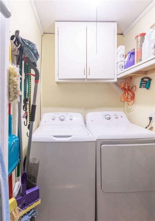washroom with ornamental molding, washing machine and dryer, and cabinet space