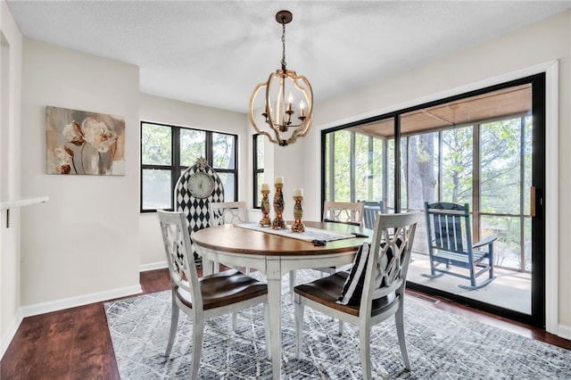 dining room with a healthy amount of sunlight, baseboards, wood finished floors, and a notable chandelier