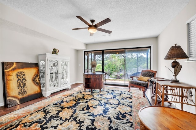 interior space featuring baseboards, a ceiling fan, a textured ceiling, and wood finished floors