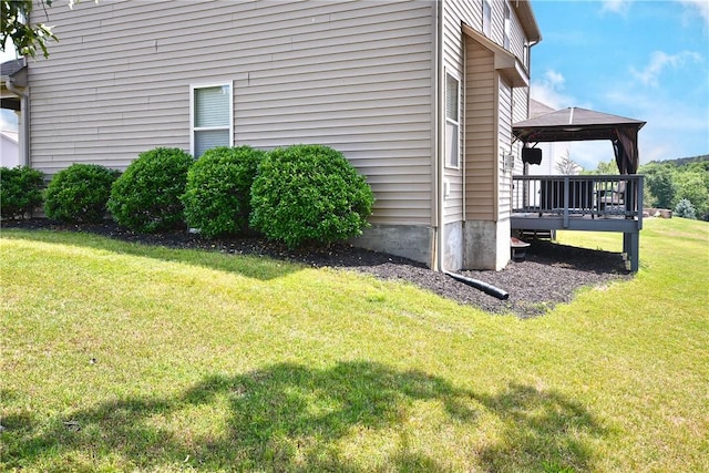 view of side of property featuring a lawn, a gazebo, and a wooden deck