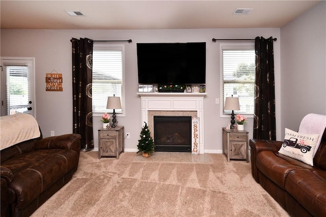 carpeted living area featuring a wealth of natural light, a fireplace, and visible vents