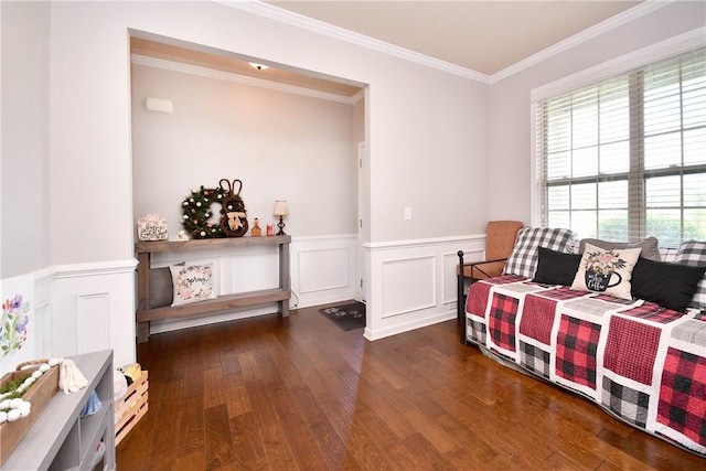 sitting room featuring crown molding, wainscoting, wood finished floors, and a decorative wall