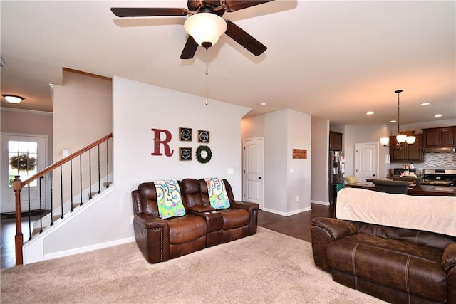 living room with baseboards, recessed lighting, stairs, and ceiling fan with notable chandelier