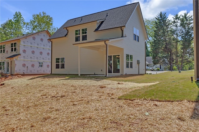 rear view of property featuring roof with shingles and a lawn