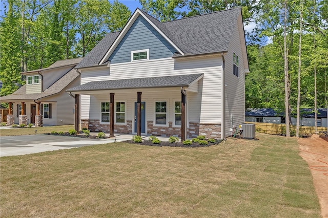 view of front of property with a porch, roof with shingles, central AC, and a front yard