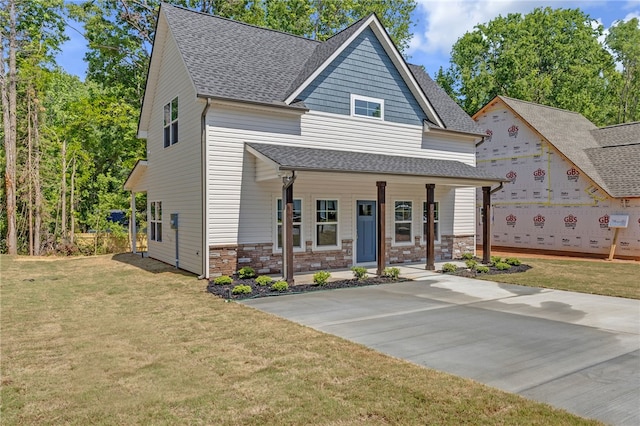 view of front of home featuring roof with shingles, a porch, and a front yard