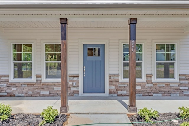 view of exterior entry with a porch and stone siding