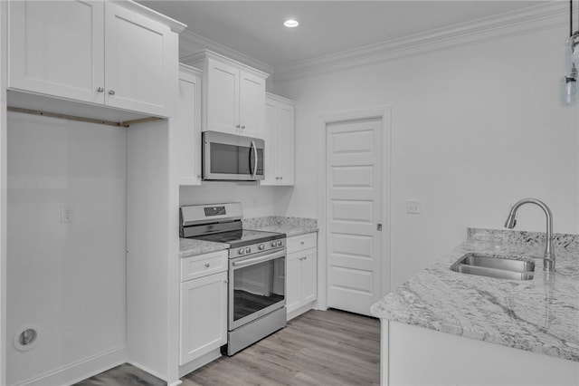 kitchen with crown molding, white cabinets, a sink, light wood finished floors, and appliances with stainless steel finishes