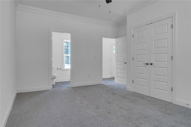 unfurnished bedroom with carpet floors, ornamental molding, baseboards, and a closet