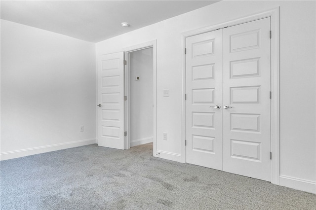 unfurnished bedroom featuring carpet floors, baseboards, and a closet