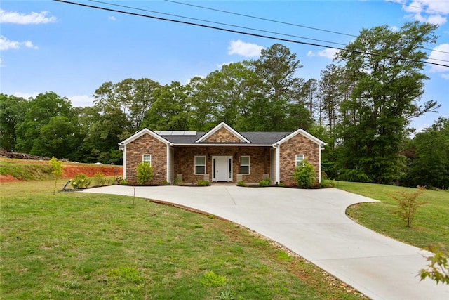 ranch-style home with concrete driveway, a front yard, solar panels, and stone siding
