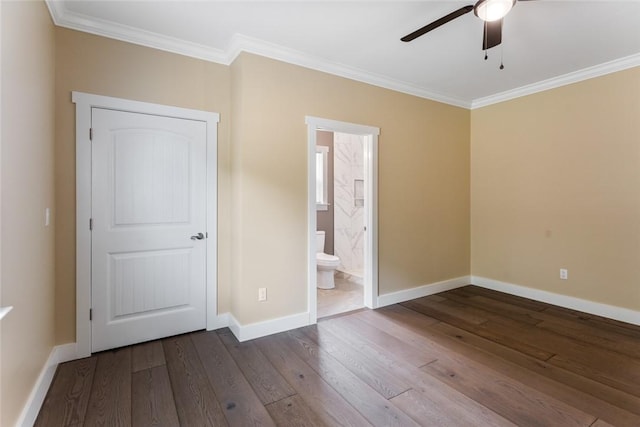 unfurnished bedroom featuring baseboards, ornamental molding, ensuite bathroom, and hardwood / wood-style flooring