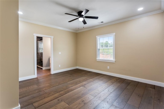 empty room with crown molding, baseboards, dark wood-type flooring, and visible vents
