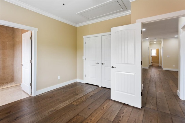 unfurnished bedroom with attic access, crown molding, baseboards, a closet, and dark wood-type flooring