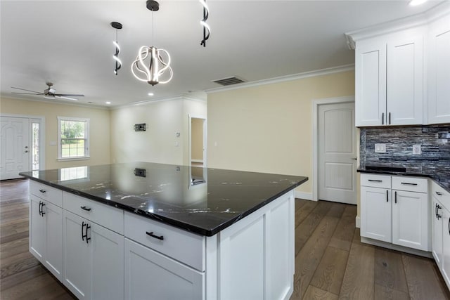 kitchen with visible vents, crown molding, dark wood-style floors, a ceiling fan, and backsplash