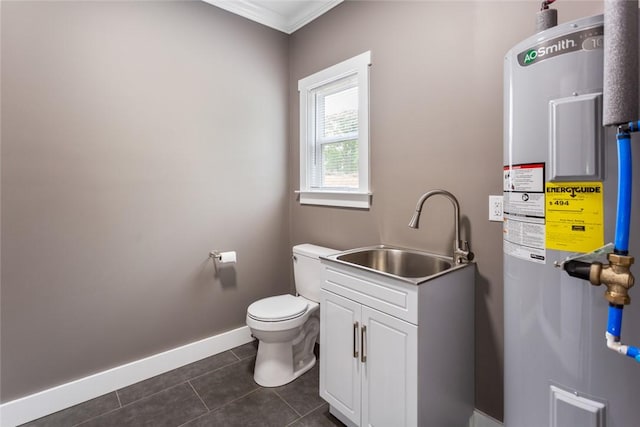 bathroom featuring a sink, tile patterned floors, water heater, baseboards, and ornamental molding