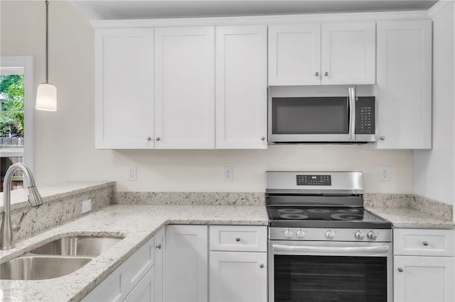 kitchen featuring white cabinets, light stone countertops, appliances with stainless steel finishes, and a sink