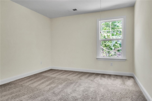 carpeted spare room featuring visible vents and baseboards