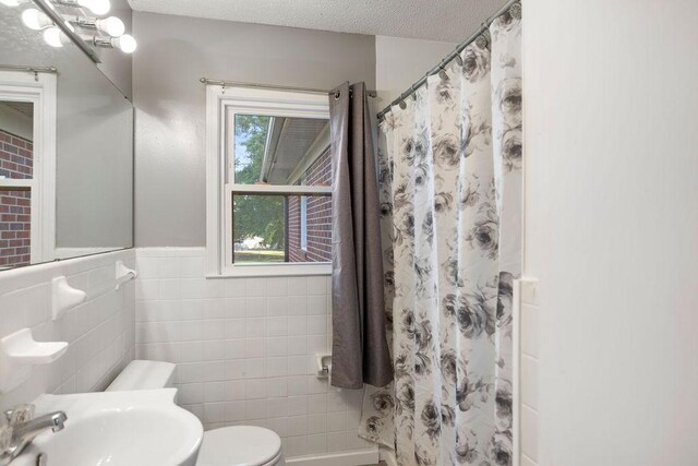 302 Jasmine Dr, Anderson, SC 29625 - full bathroom with wainscoting, a sink, toilet, a shower with shower curtain, and tile walls