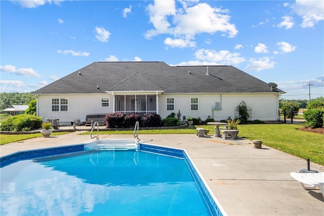 rear view of property featuring roof with shingles, stucco siding, an outdoor pool, a patio area, and a yard