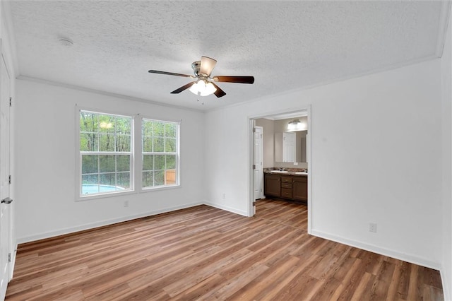 unfurnished bedroom featuring light wood-style floors, a textured ceiling, baseboards, and ceiling fan
