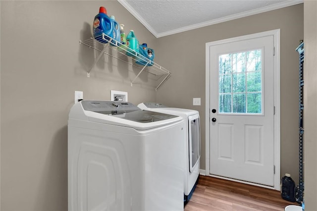 laundry area featuring laundry area, crown molding, washing machine and dryer, light wood-style floors, and a textured ceiling