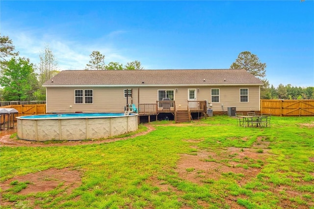 back of house with a fenced in pool, a fenced backyard, a yard, and a deck