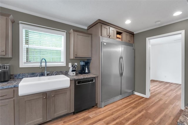 kitchen with crown molding, a sink, dishwashing machine, and built in fridge