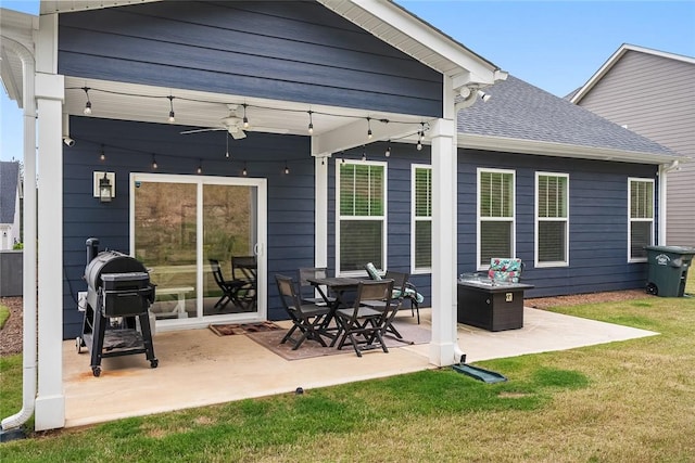 back of property with a shingled roof, a patio, ceiling fan, and a yard