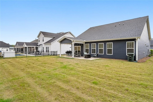 rear view of house featuring a patio, a lawn, fence, and roof with shingles